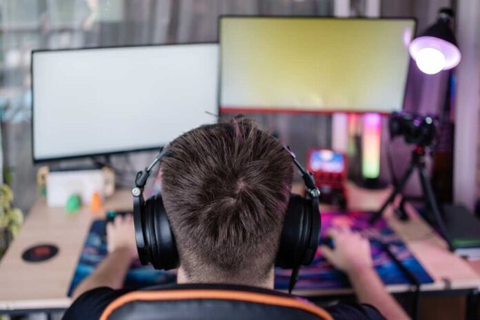 Person wearing headphones at a gaming setup with dual monitors