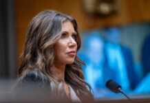 A woman testifying in a government hearing with a serious expression