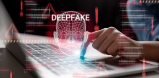 A hand interacting with a laptop displaying a deepfake warning
