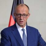 Trump’s Shock Move: Troops Leaving Germany? A government official speaking at a press conference with national flags in the background