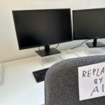 Automation Shockwave: White-Collar Jobs at Risk An office desk with two computer monitors and a chair labeled 'REPLACED BY AI'
