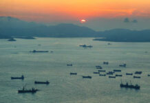 A scenic view of cargo ships on water during sunset
