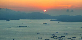 A scenic view of cargo ships on water during sunset