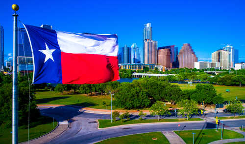 Texas flag waving in front of the Austin skyline