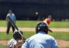 A young baseball player preparing to bat as a pitcher throws the ball