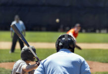 A young baseball player preparing to bat as a pitcher throws the ball