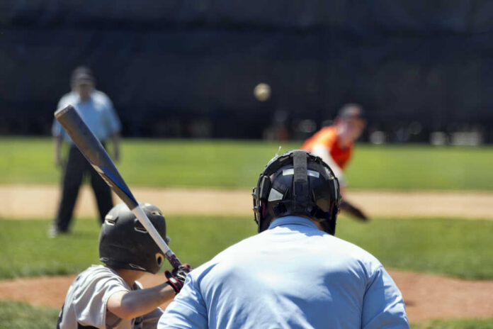 A young baseball player preparing to bat as a pitcher throws the ball