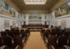 Interior view of a courtroom with wooden benches and large murals