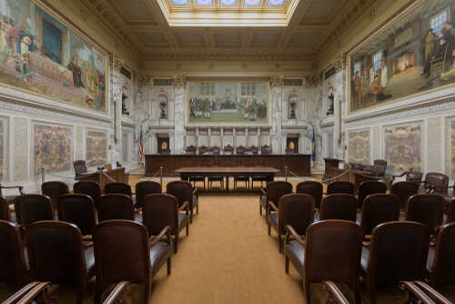 Interior view of a courtroom with wooden benches and large murals