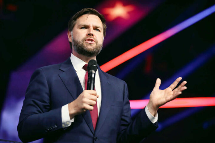 Man in suit speaking with microphone on stage.