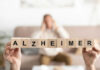 Blocks spelling Alzheimer in foreground, blurred person behind.