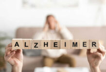 Blocks spelling Alzheimer in foreground, blurred person behind.