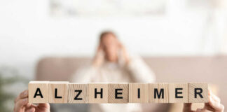 Blocks spelling Alzheimer in foreground, blurred person behind.