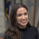 AOC’s Ambitions: More Than Presidential Buzz? A person smiling, wearing a black shirt.