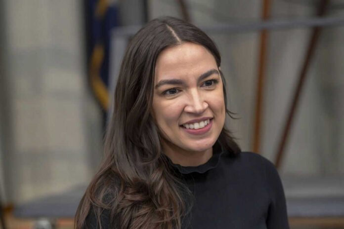 alexandria-ocasio-cortez-703778517 A person smiling, wearing a black shirt.