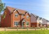 Red-brick suburban house in a sunny neighborhood.