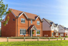 Red-brick suburban house in a sunny neighborhood.