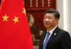 Xi’s War Warning STUNS Trump Crowd Person standing near a Chinese flag indoors