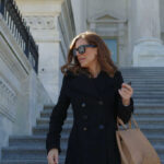 Trump Receipts Wreck Mace Narrative Woman in black coat on stone steps outside a classical building