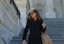 Woman in black coat on stone steps outside a classical building