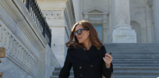 Woman in black coat on stone steps outside a classical building