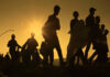 Silhouetted figures walking against a sunset backdrop