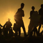 Silhouetted figures walking against a sunset backdrop
