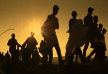 Silhouetted figures walking against a sunset backdrop