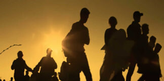 Silhouetted figures walking against a sunset backdrop