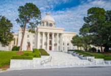 Exterior view of a historic government building with a dome and landscaped grounds