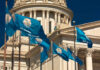 Oklahoma state flags waving in front of the State Capitol building
