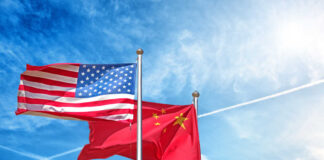 Flags of the United States and China waving against a blue sky