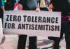 Protesters holding a sign that reads 'ZERO TOLERANCE FOR ANTISEMITISM'