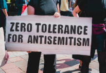 Protesters holding a sign that reads 'ZERO TOLERANCE FOR ANTISEMITISM'