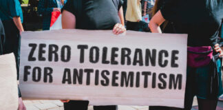Protesters holding a sign that reads 'ZERO TOLERANCE FOR ANTISEMITISM'