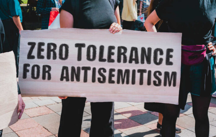 Protesters holding a sign that reads 'ZERO TOLERANCE FOR ANTISEMITISM'