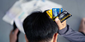 Person holding multiple credit cards while looking stressed