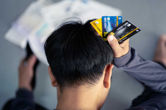 Person holding multiple credit cards while looking stressed