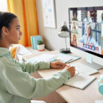 A young girl participating in a virtual meeting on a computer
