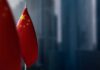 Close-up of the Chinese flag on a flagpole with a blurred urban background
