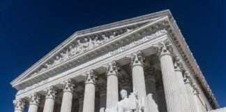 The Supreme Court building featuring columns and a statue of justice