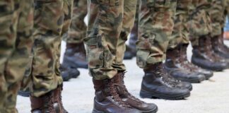 Row of soldiers in camouflage uniforms standing at attention with military boots