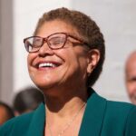 A woman with glasses smiling joyfully at an outdoor event
