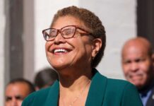 A woman with glasses smiling joyfully at an outdoor event