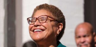 A woman with glasses smiling joyfully at an outdoor event