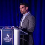 Daily Wire COLLAPSE—What’s Really Happening? A man in a gray suit speaking at a podium during a political dinner