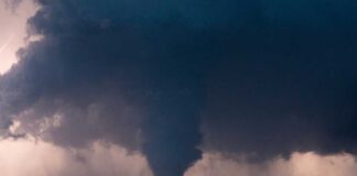 A tornado forming under dark storm clouds with lightning in the background