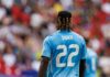 Soccer player wearing a blue jersey with the name Doku and number 22, facing away from the camera