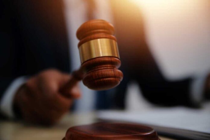 A gavel being struck on a desk in a courtroom setting
