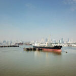 Tension Soars: Gaza-Bound Flotilla Stopped Cargo ships docked in a harbor with a city skyline in the background